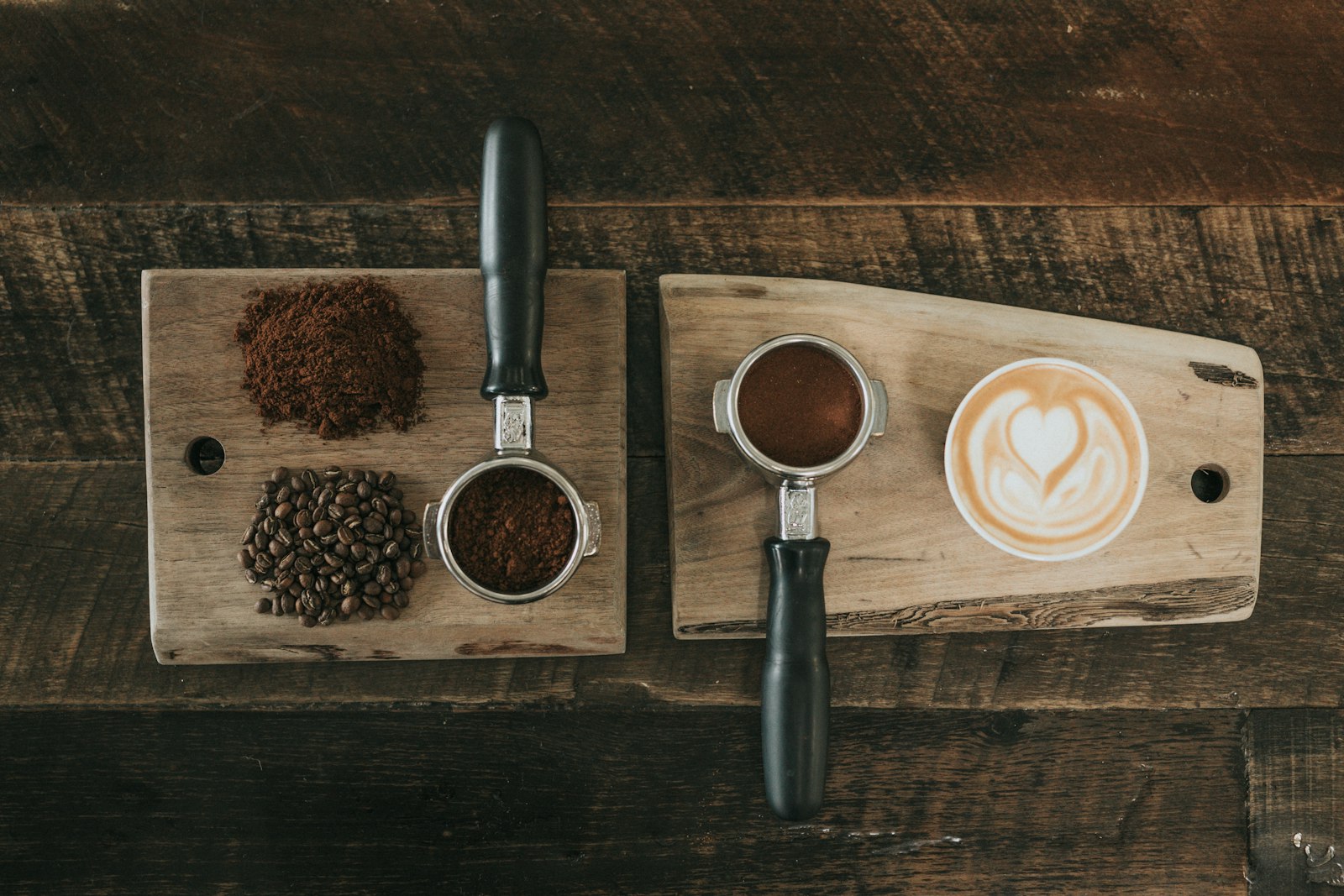 Coffee grounds, roasted beans, and a portafilter arranged on dark wood